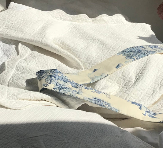 BAZAR Atelier Sablon : Foulard en toile de Jouy, modèle Jouy de Fruits bleu. Le bandeau est posé sur le lit. 